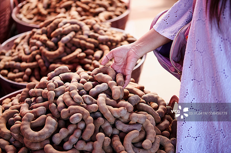在泰国碧差汶的市场摊位上，妇女购买成熟甜罗望子果实的身体中部照片图片素材