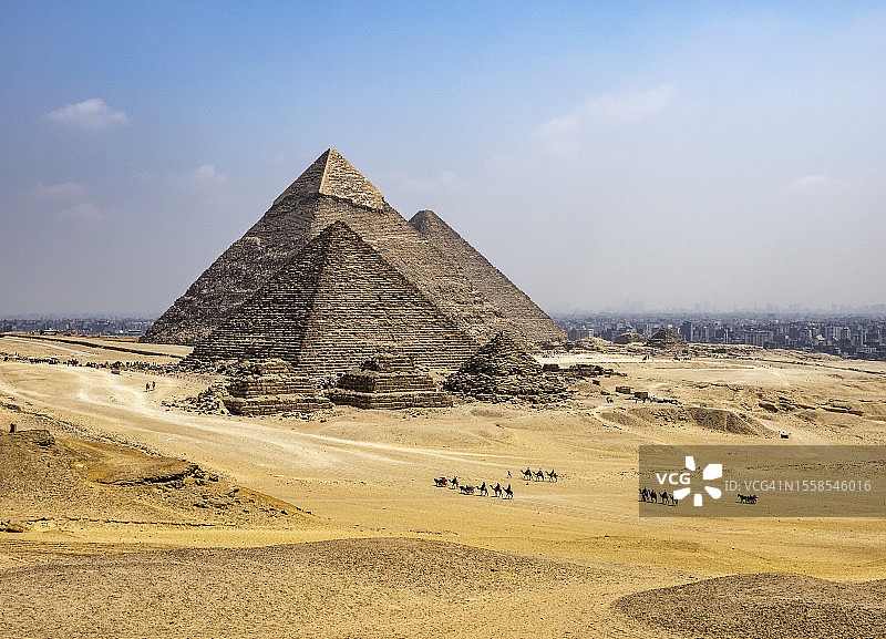 埃及吉萨金字塔景观，沙丘上有成队的骆驼图片素材