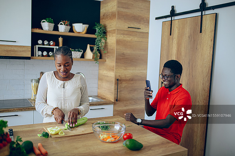 年轻黑人夫妇在做饭时用手机拍照图片素材