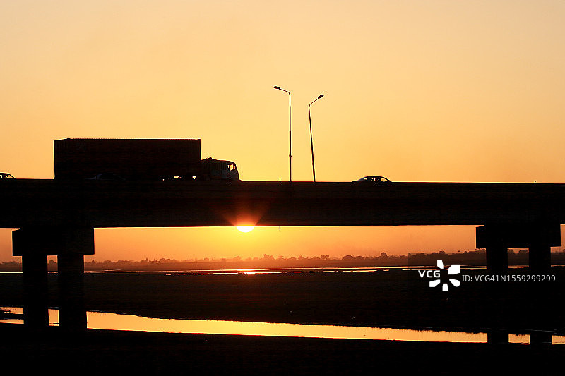 日落时分，单车道上，半挂卡车在桥上飞驰图片素材