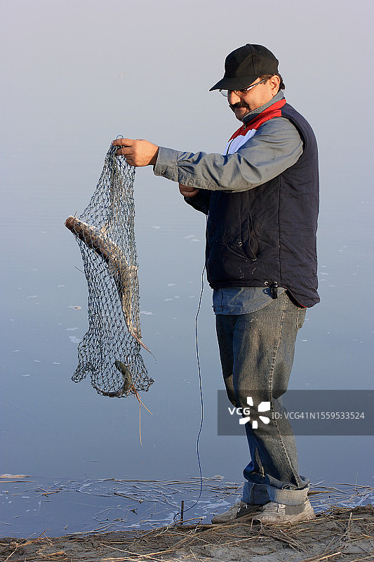 男子手持渔网捕鱼后图片素材