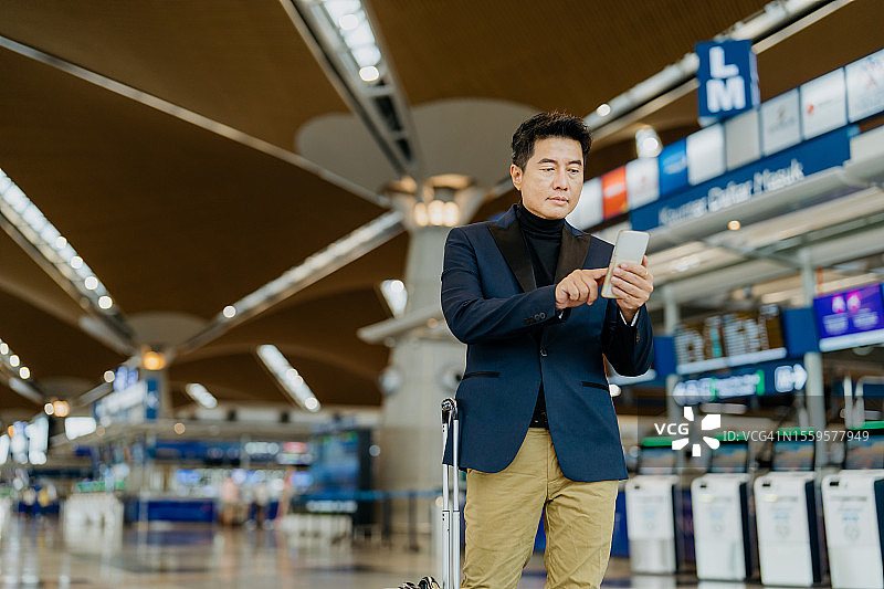 在机场使用智能手机的亚洲商人图片素材