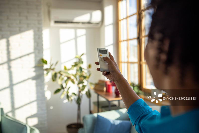 女人打开客厅里的空调图片素材
