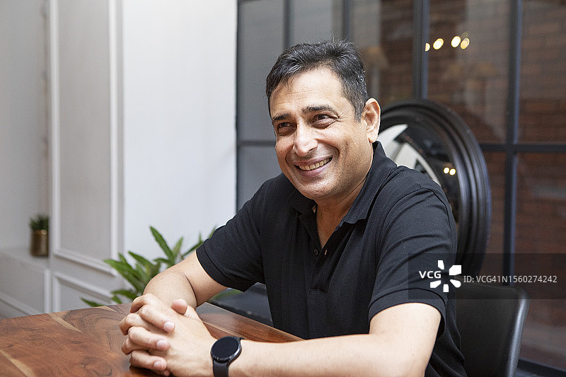 快乐的年长男人坐在桌旁图片素材