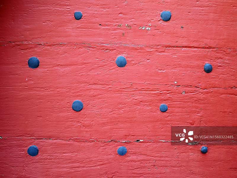 在瑞士弗里堡州格吕耶尔的红色木板古墙上，涂成蓝色的钉子头图片素材