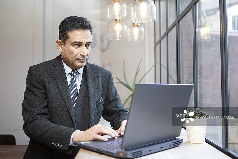 穿着正式的商人使用笔记本电脑工作图片素材