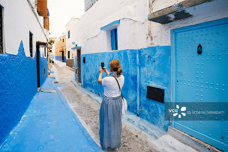 女游客在摩洛哥拉巴特老麦地那的巷子里拍照图片素材