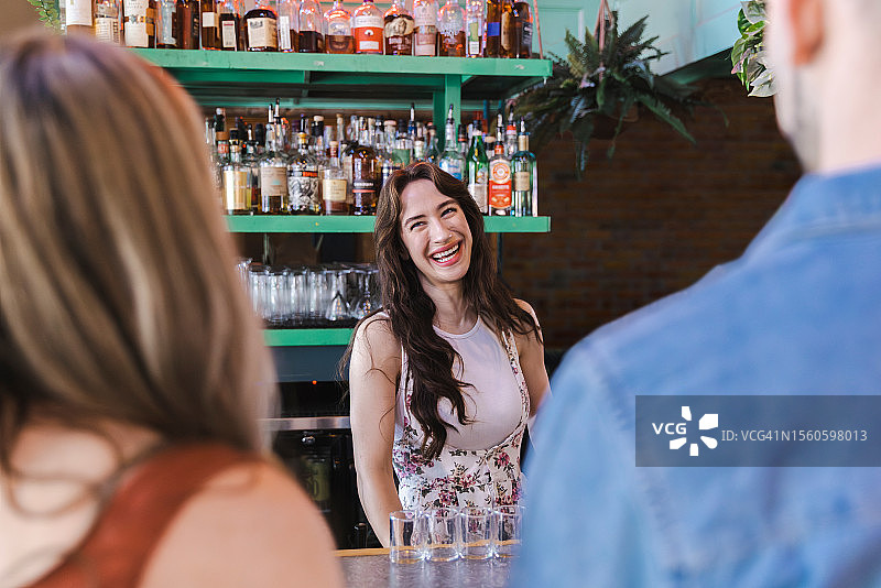 酒保在吧台后微笑地看着顾客图片素材