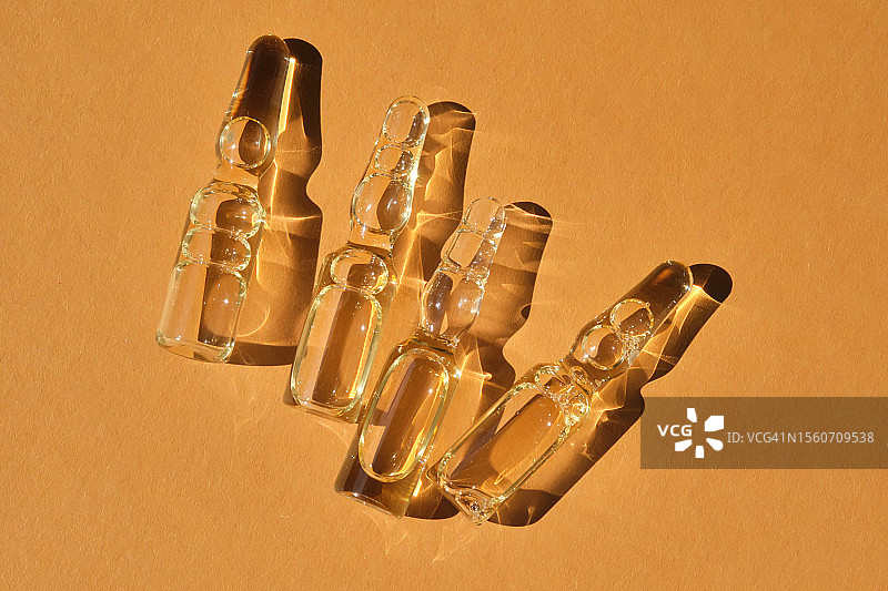 米色橙色背景上的玻璃安瓿瓶图片素材