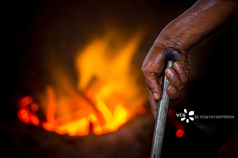 在孟加拉国达卡，男子用手持钢靠近火焰图片素材