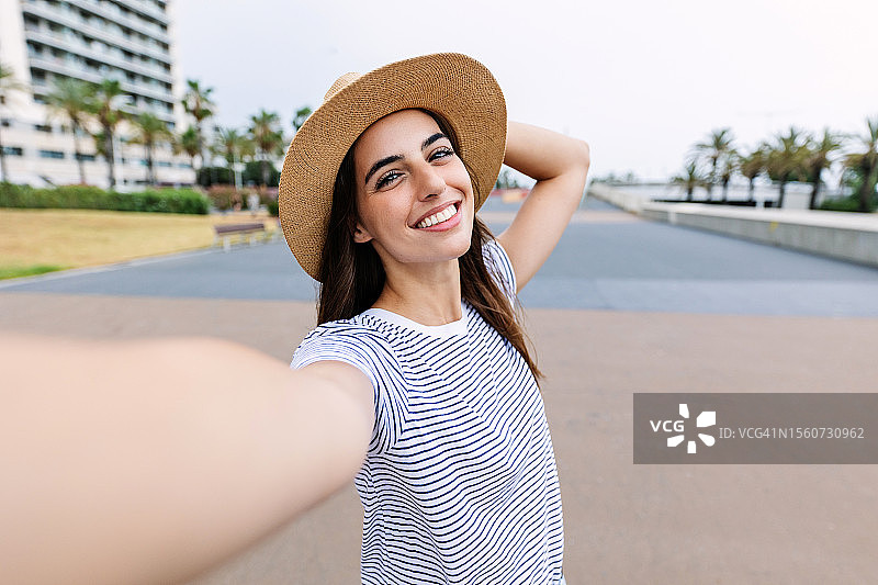 年轻女游客在街头自拍，对着手机镜头微笑图片素材