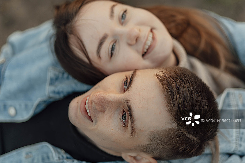 俯视视角：快乐的年轻夫妇放松地靠在彼此的肩膀上看着天空图片素材