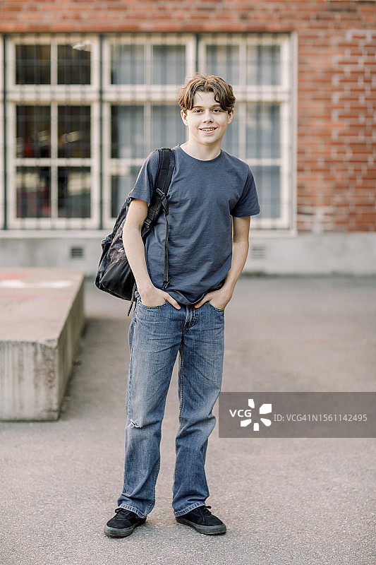 高中校园里双手插在口袋里的男学生肖像图片素材