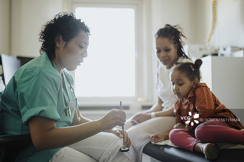 女儿科医生用叩诊锤与医院里的病人交谈图片素材