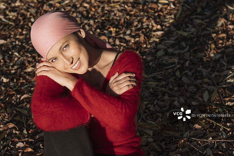 一位快乐的乳腺癌幸存者在草地上放松，双手抱膝图片素材