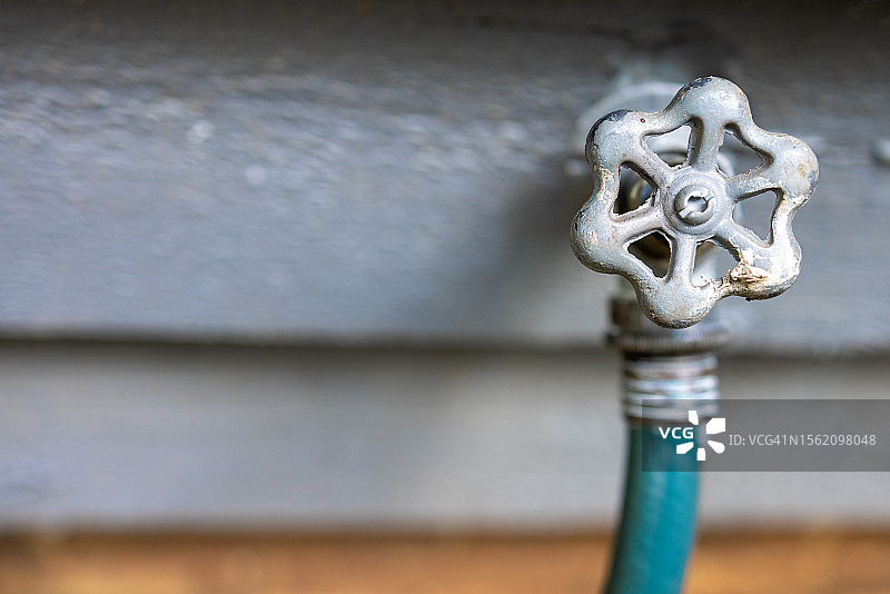 房屋外墙上的传统户外水龙头和花园软管图片素材