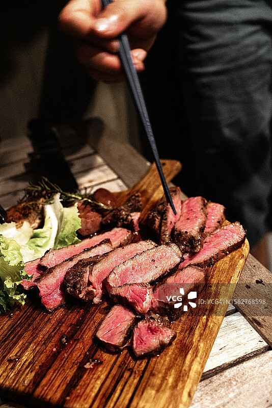 砧板上的烤牛排切片，准备用筷子夹起图片素材