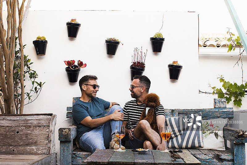 在餐厅里和他们的狗愉快聊天的两个男人图片素材