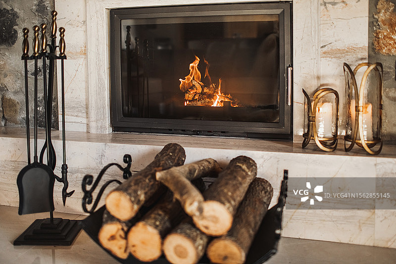 燃烧的壁炉旁的木柴和壁炉工具图片素材