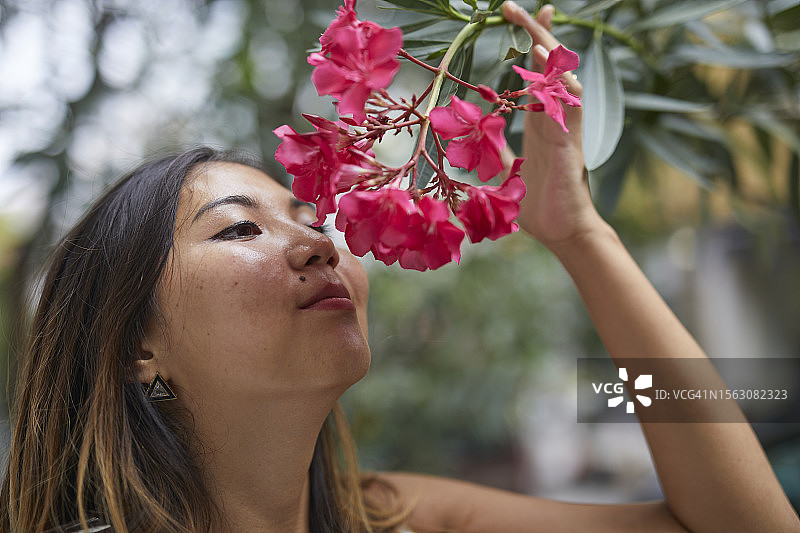 一位年轻女士在享受红花的香味图片素材