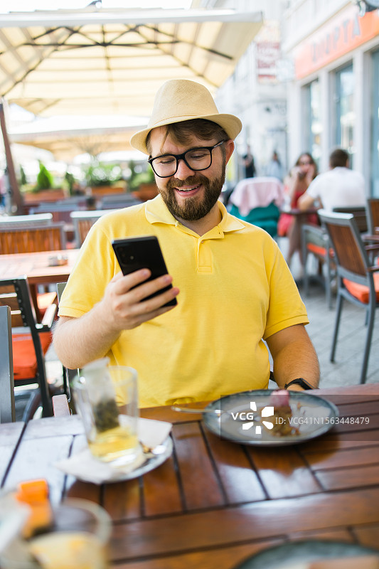 男游客坐在街边餐厅上网查阅城市信息图片素材