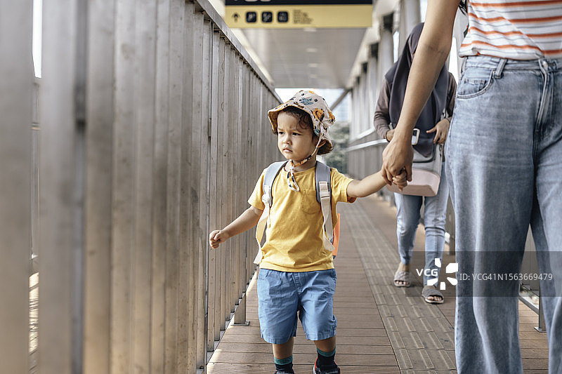 母亲和儿子在城市人行天桥上行走，背着背包图片素材