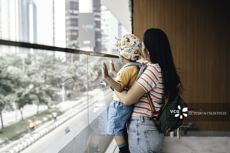 母亲和儿子在城市人行天桥上行走，背着背包图片素材