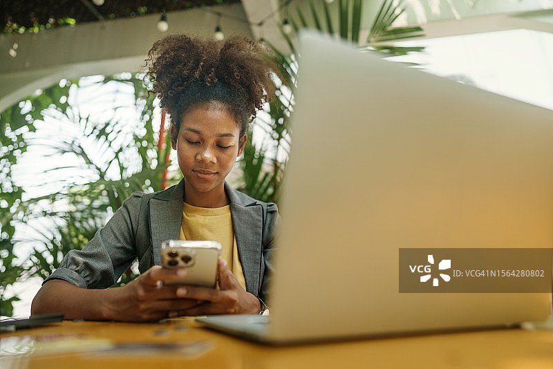 咖啡馆里用笔记本电脑的年轻美籍混血自由职业女性面部积极情绪侧视图图片素材