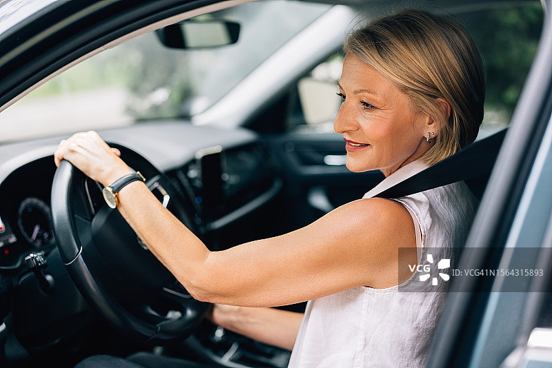 快乐美丽的白人女商人开车时看向别处图片素材
