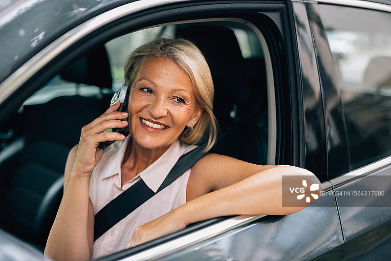 快乐美丽的白人女商人坐在车里，一边打电话一边看向别处图片素材