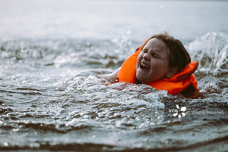 戴着充气救生衣在河里溺水，哭喊着求救的受惊的孩子图片素材