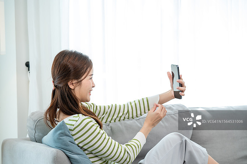 坐在客厅沙发上的漂亮亚洲女性图片素材