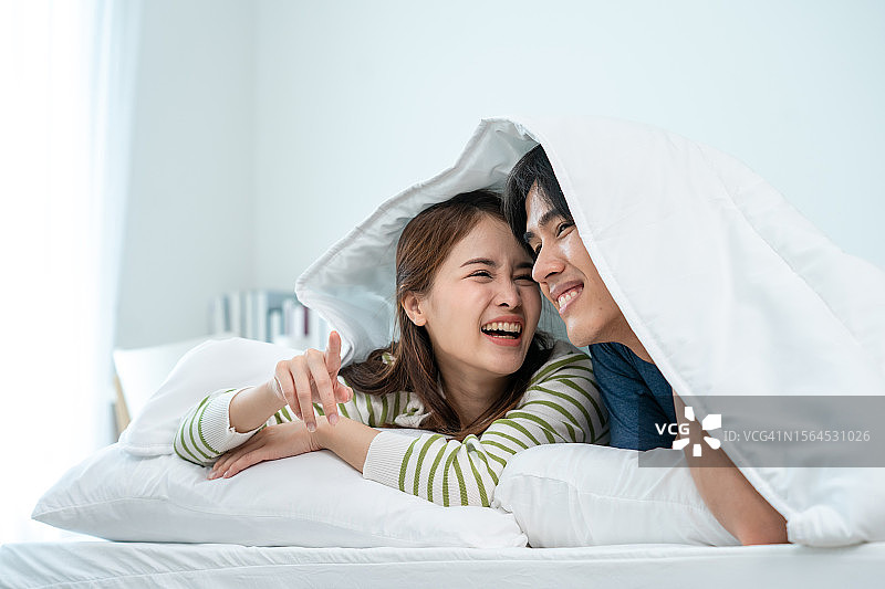 快乐年轻情侣在卧室床上休憩图片素材