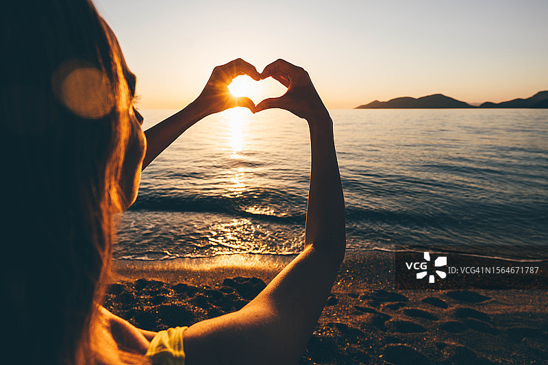 海上日落时分，双手剪影比心图片素材