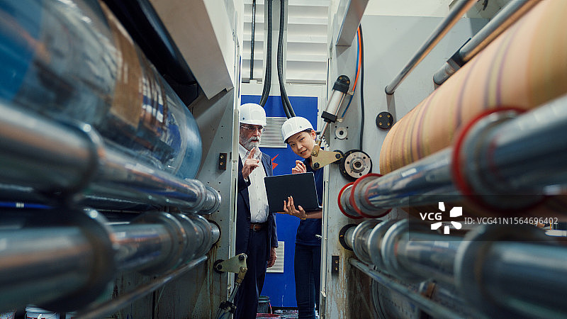 职业男性工业工程师在工厂使用笔记本电脑与工人交谈图片素材