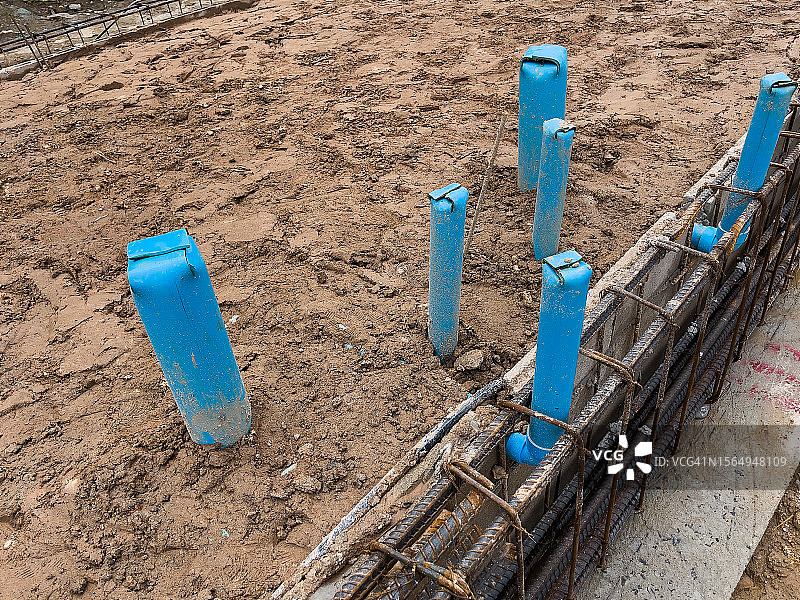 工人在带有钢筋和混凝土的建筑地基下安装污水塑料管道图片素材