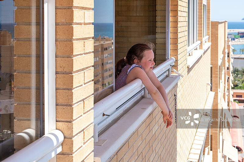 7岁的白人女孩在高楼层窗口向外看图片素材