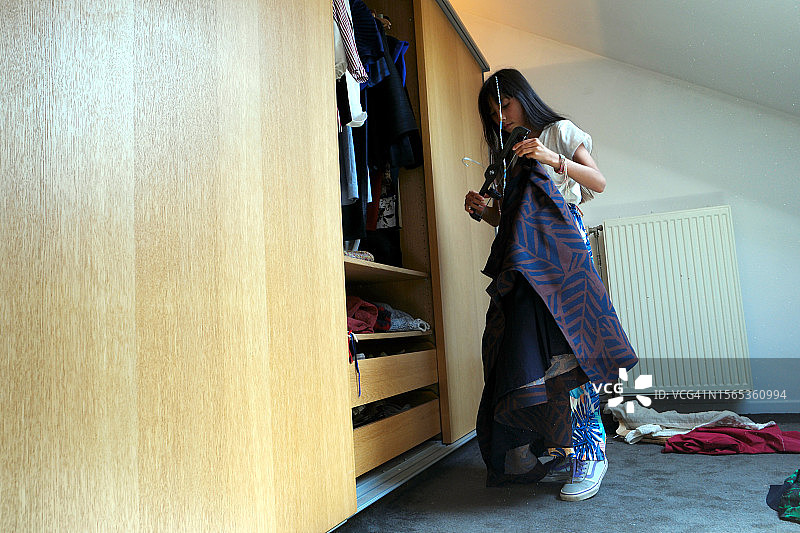 混血青少年在衣柜里挑选衣服图片素材