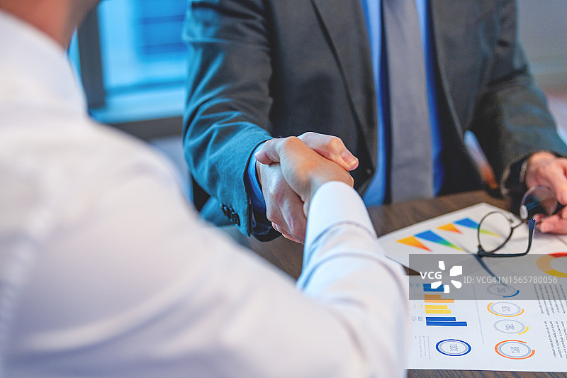 商务男士握手特写，穿着商务服装，有文件和电脑图片素材