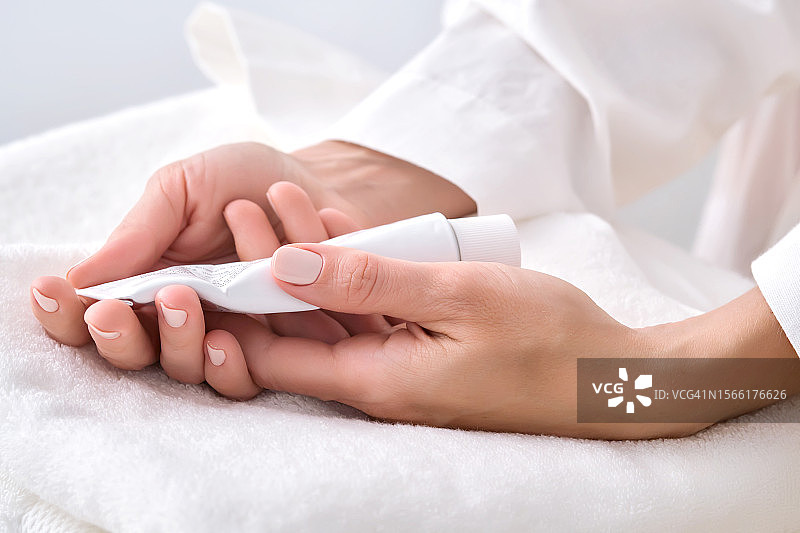 女人手拿着白色乳霜软管图片素材