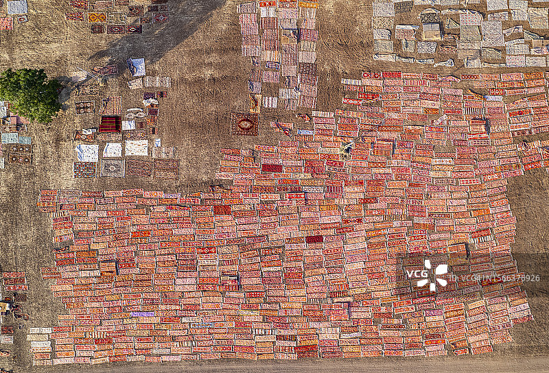 阳光下晾晒的数十条手工编织地毯图片素材