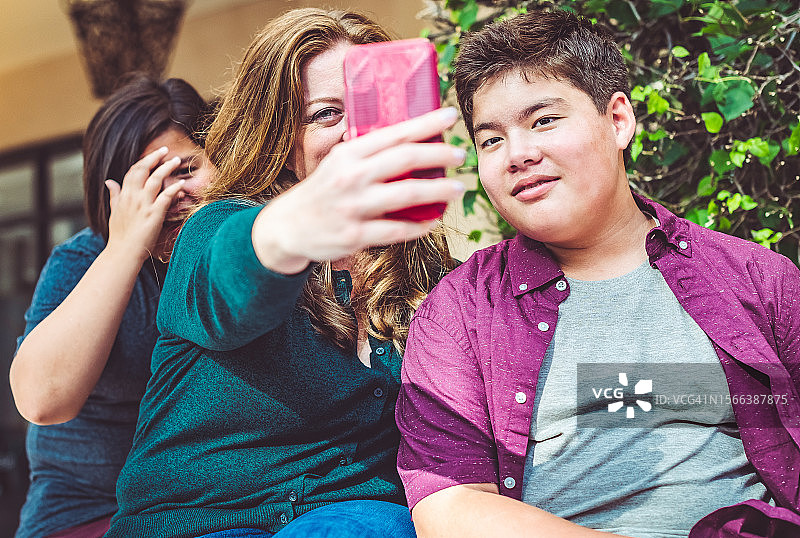 母亲与混血亚裔青少年子女在户外自拍图片素材