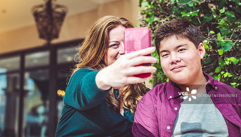 母亲与混血亚洲裔青少年儿子在户外自拍图片素材