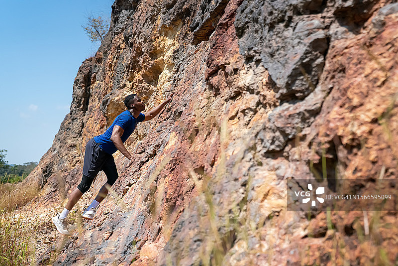 一个强壮的男人攀登岩石山，登山徒步，攀岩路线图片素材