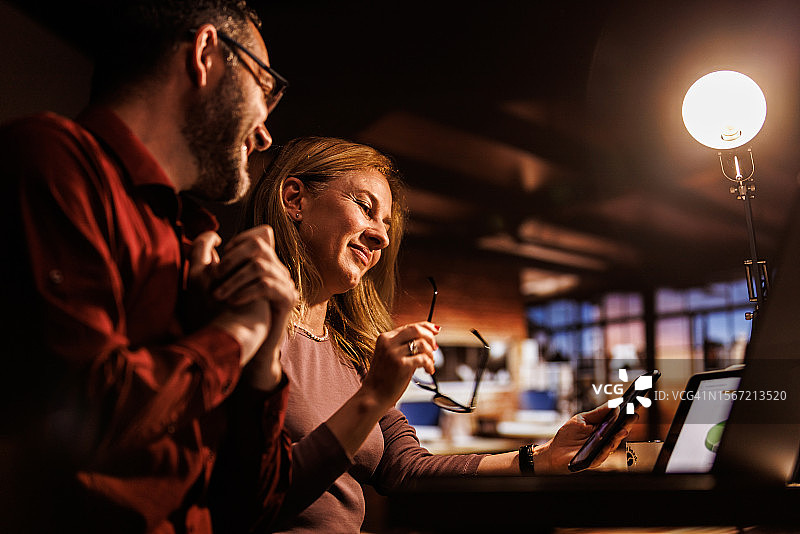 在办公室加班时与同事视频聊天的两位商人图片素材