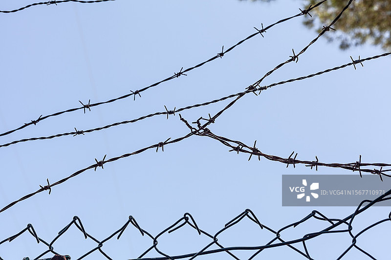 蓝色天空背景下的铁丝网围栏轮廓图片素材