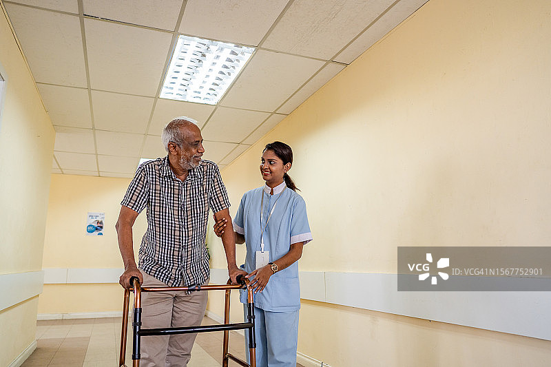护理员协助老年男子使用助行器图片素材