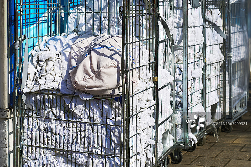街边装满酒店待洗衣物的金属篮手推车（正面视角）图片素材