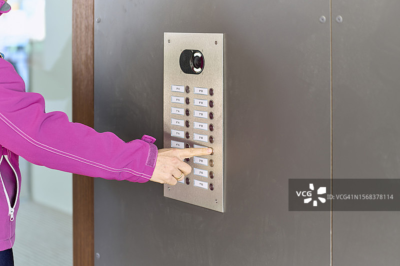 女人触摸门卫门铃按钮的手部特写，侧视图片素材