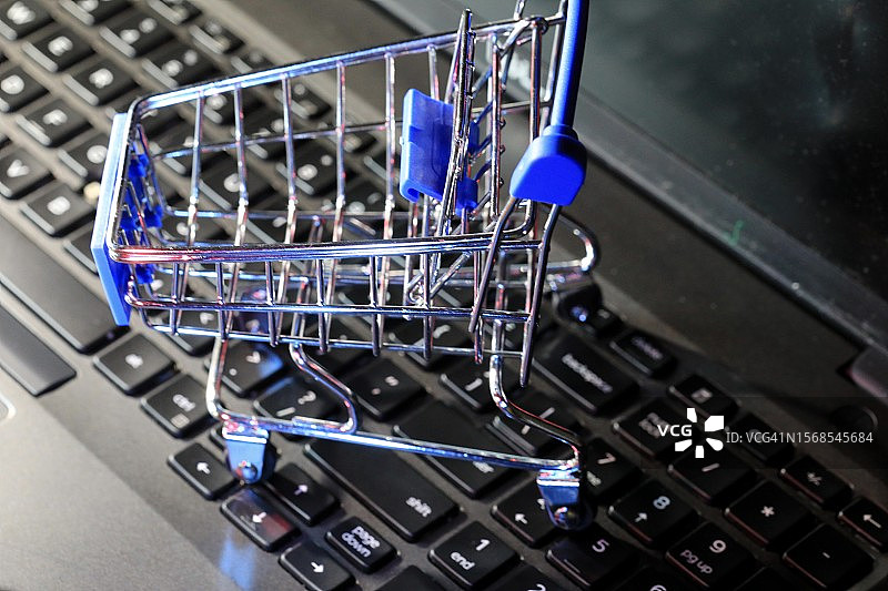 带复制空间的手提电脑上的小型购物手推车：在线购物概念图片素材